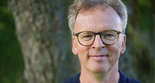 Lars H. Mitglied der Online Marketing Community lächelt vor einem Baum.